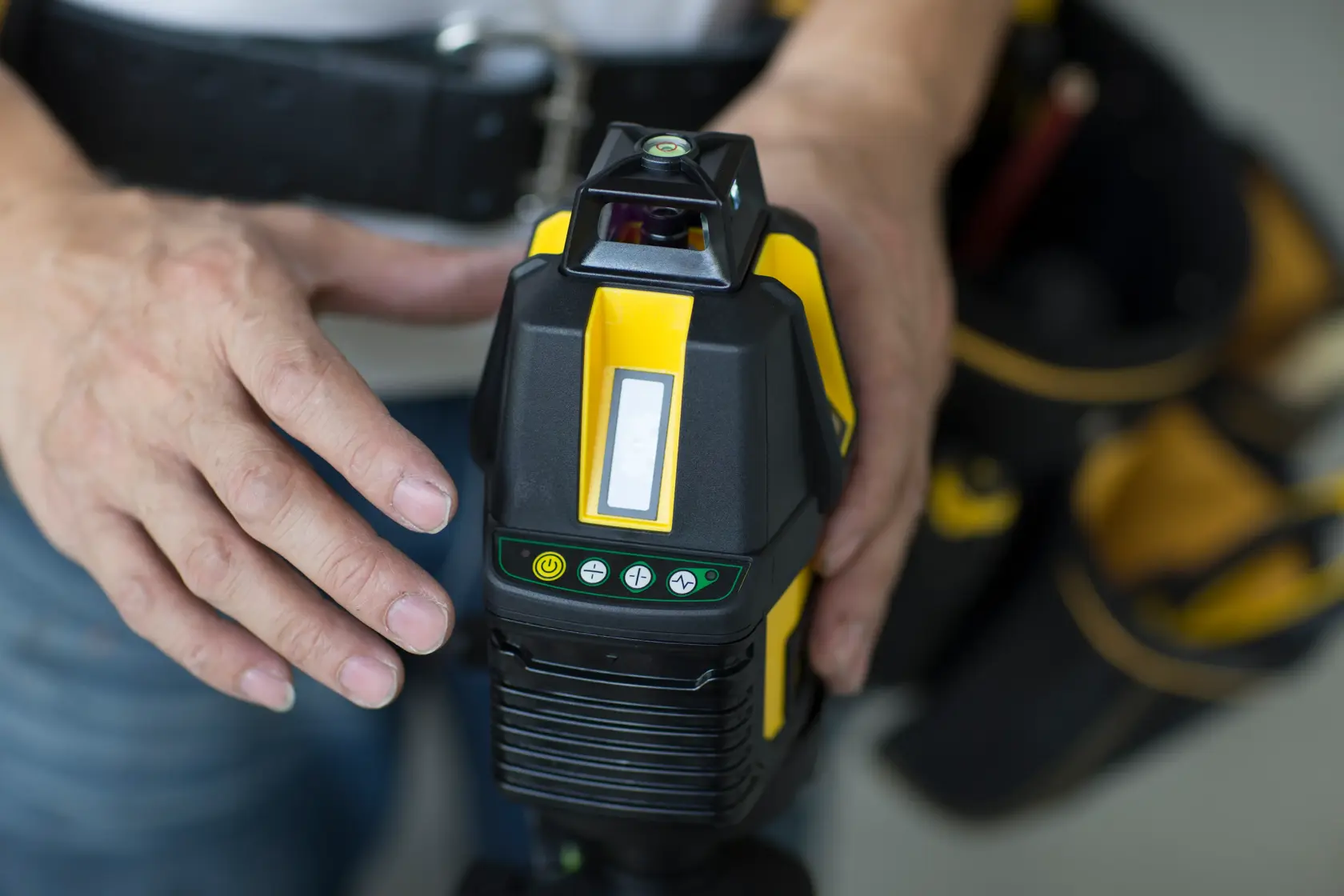 STANLEY STHT77524-1 laser level device held by a person, close-up of controls and yellow-black design.
