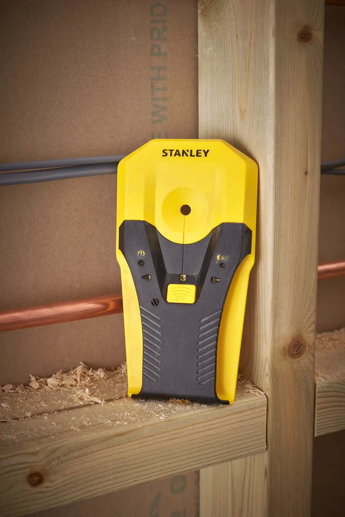 Stanley STHT77588-0 stud finder, yellow and black, angled vertically on wooden stud, photography.