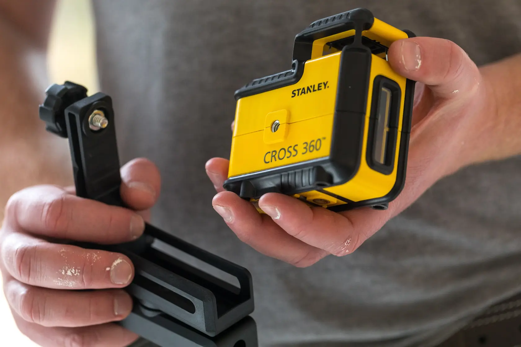 STANLEY STHT77640-1 yellow CROSS 360° laser level held in hand, with mounting bracket visible.