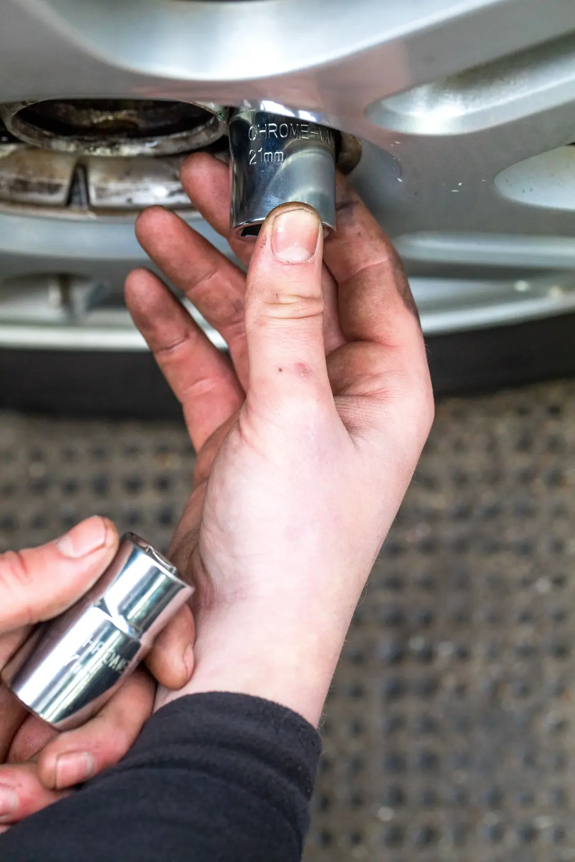 STANLEY STHT80890-0 socket being used to remove a car wheel nut, close-up hand view.