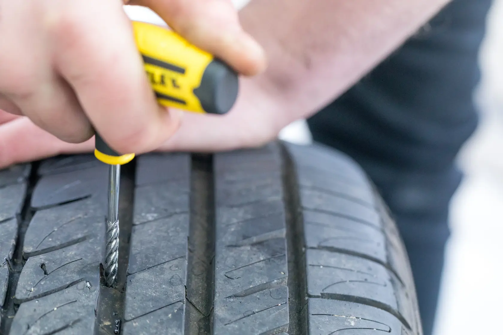 STANLEY STHT80891-0 tire repair tool in use on a car tire tread, close-up photography.
