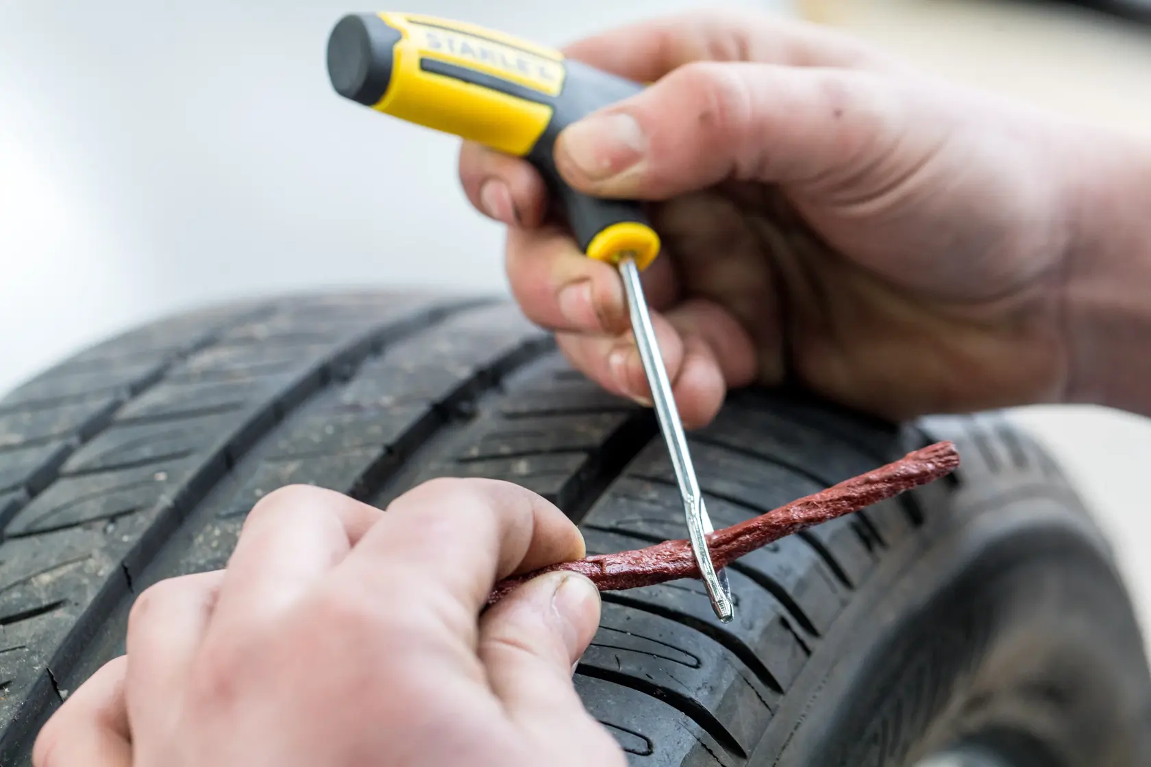 STANLEY STHT80891-0 tire repair tool used to insert plug in car tire, close-up photo.