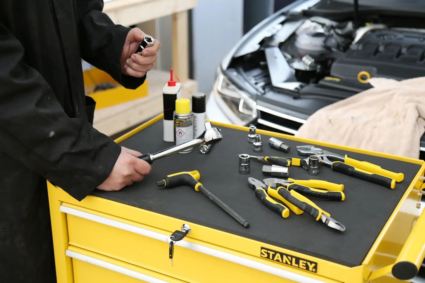 STANLEY STMT1-75063 tool assortment with yellow handles on top of tool chest, mechanic holding socket.