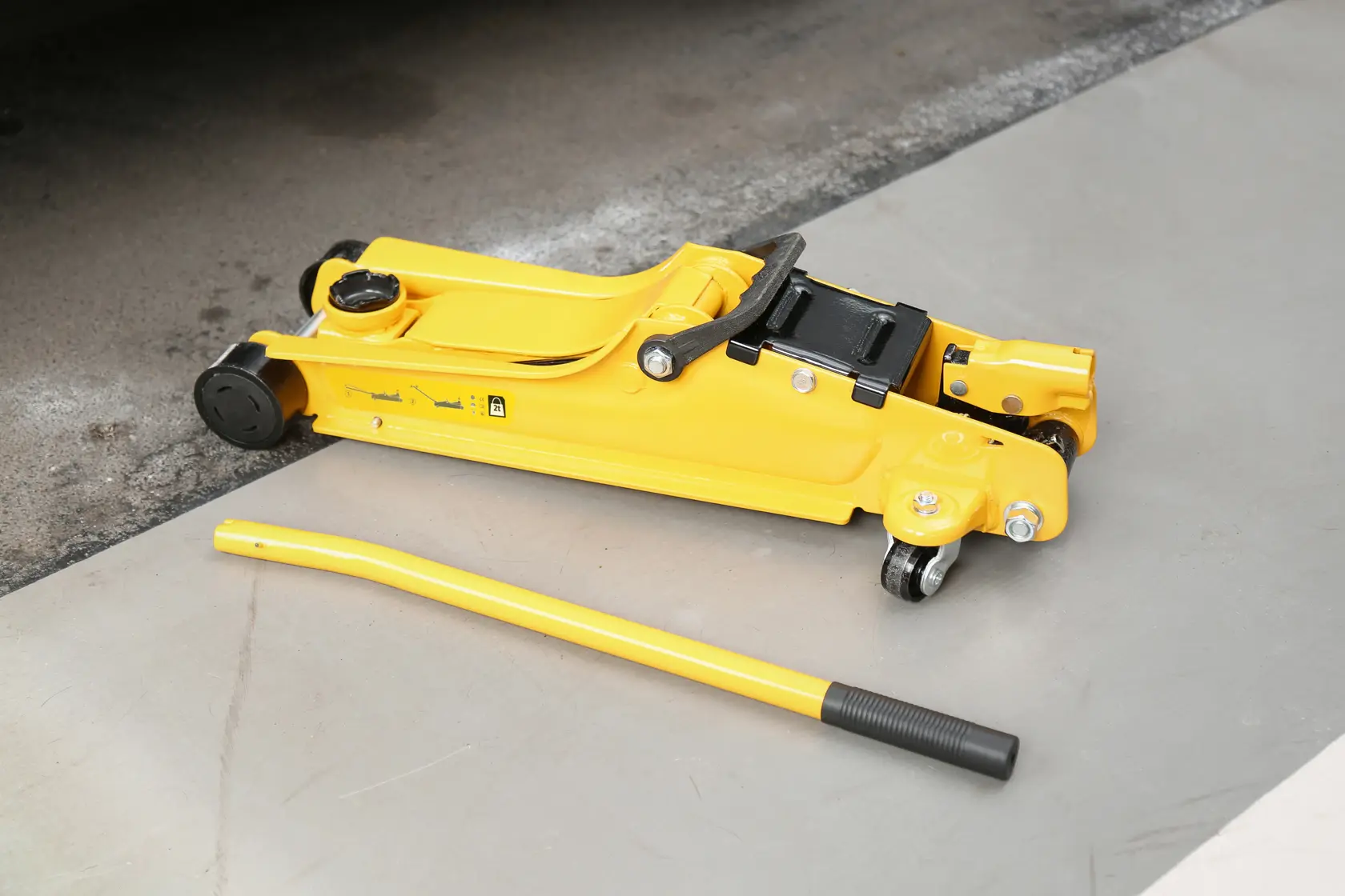 STANLEY STMT81251-1 yellow hydraulic floor jack with handle, side angle, on concrete surface.
