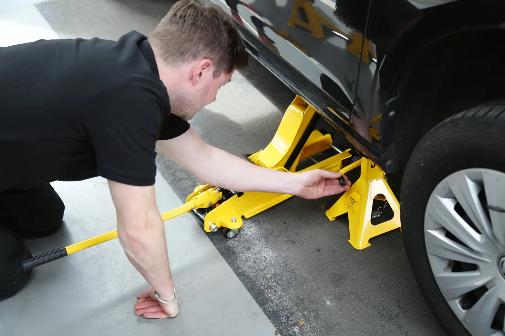 STANLEY STMT81255-1 yellow jack stand and car jack in use under vehicle, side view, automotive accessory.