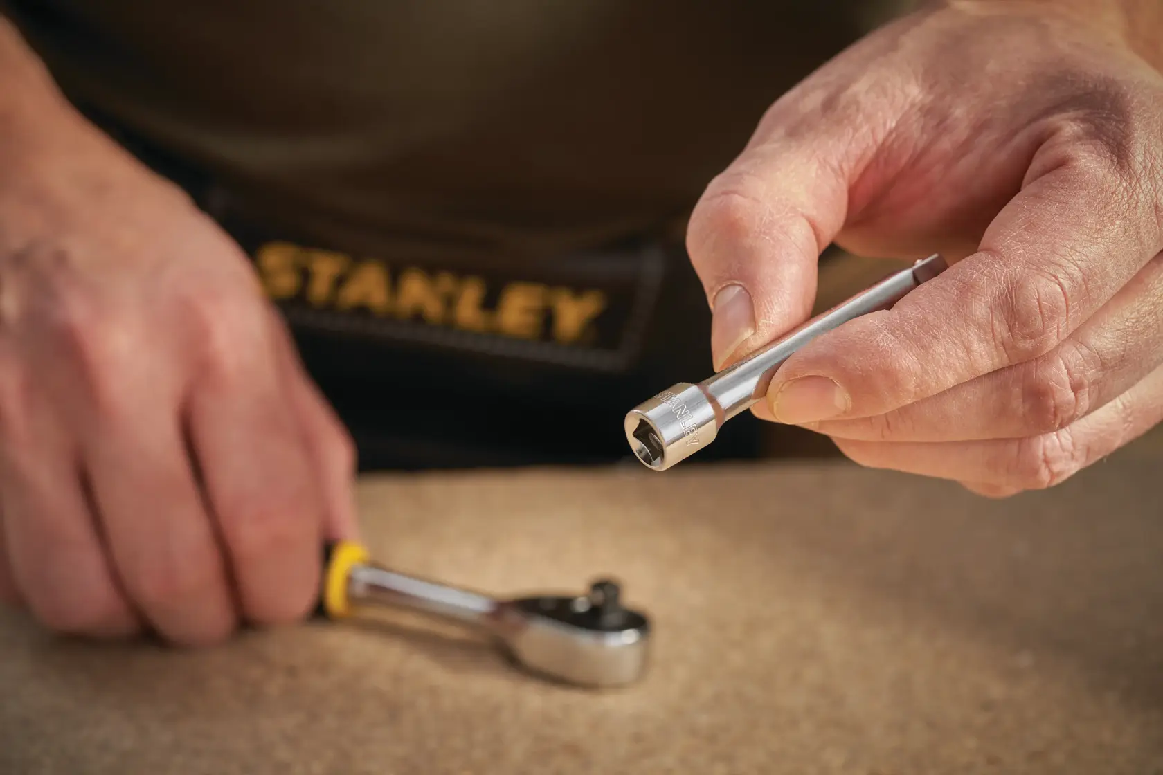 STANLEY STMT86006-0 socket extension bar held by hand, ratchet in background, close-up photo.