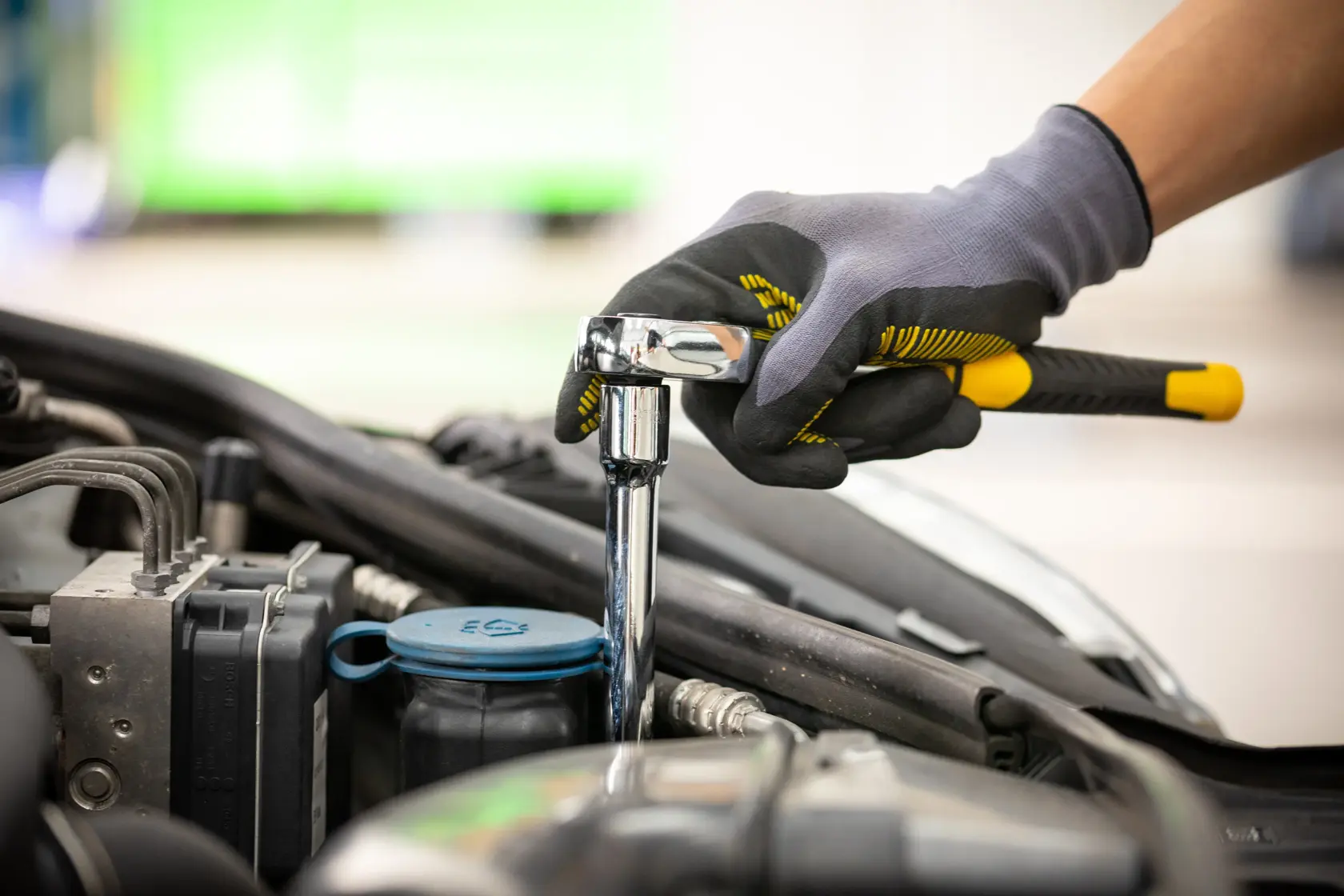 STANLEY STMT86006-0 ratchet wrench used for car engine maintenance, close-up of gloved hand holding tool.
