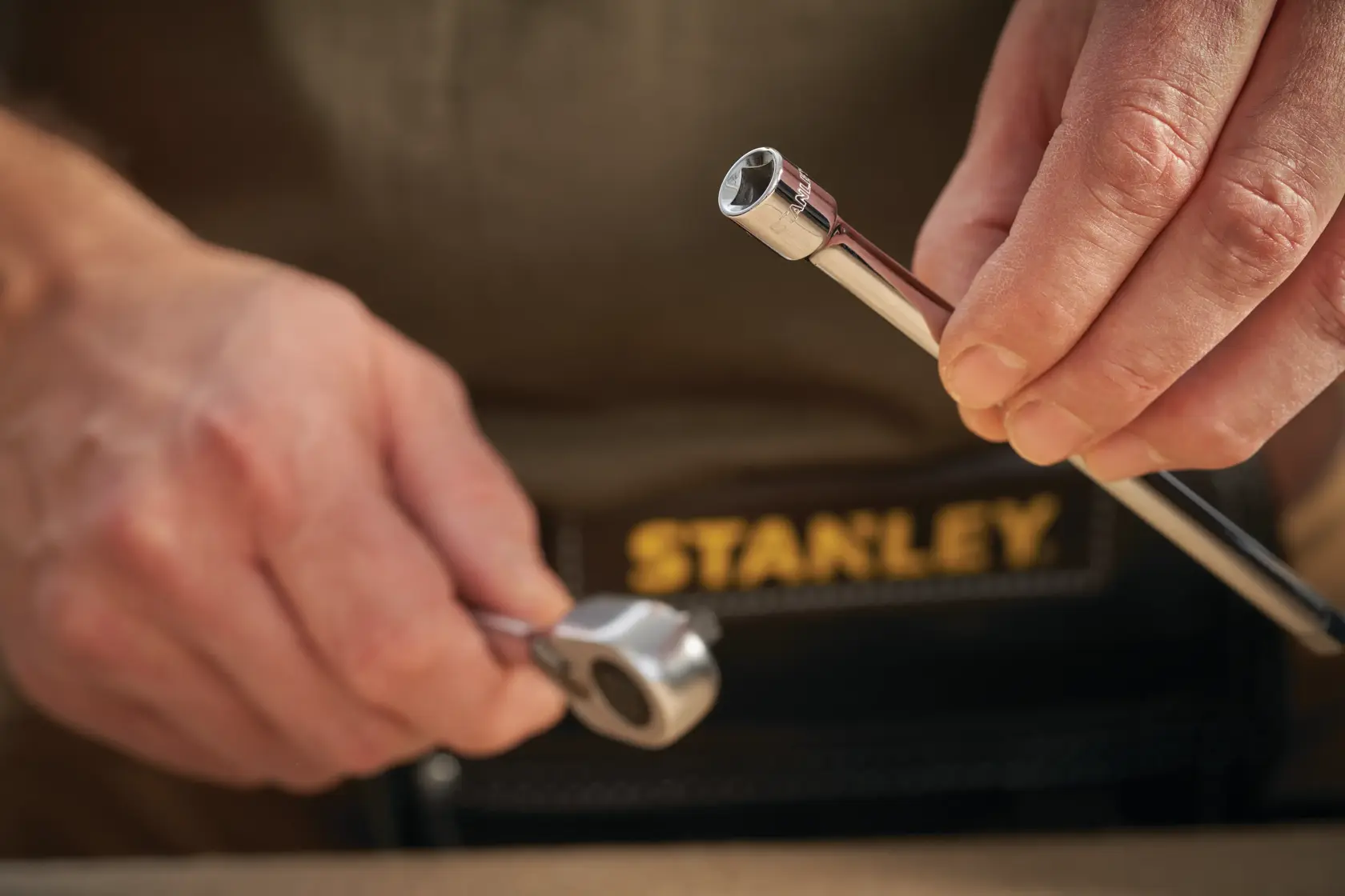Photo of STANLEY STMT86007-0 ratchet and socket, close-up in hand, with tool belt visible.