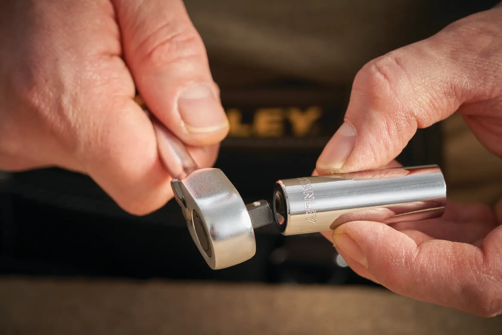 STANLEY STMT86099-0 socket wrench and chrome socket, close-up of hands holding tool.