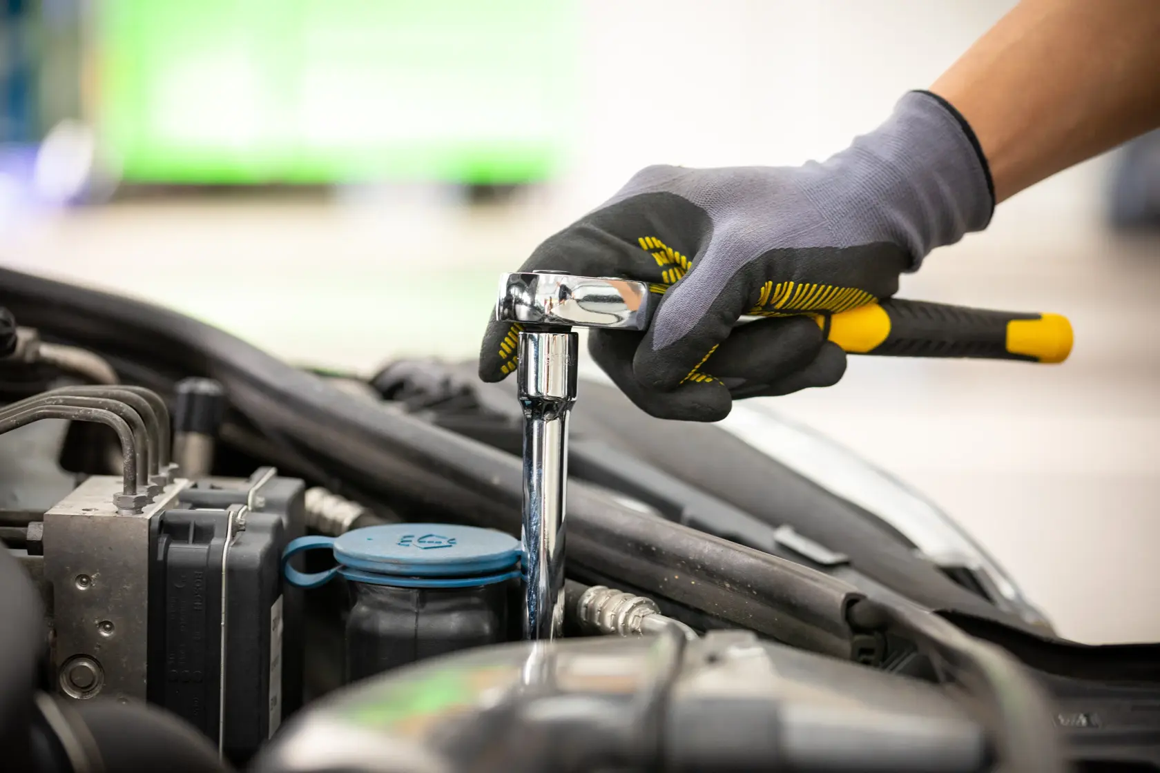 STANLEY STMT86206-0 ratchet wrench used on car engine, gloved hand grip, side angle, automotive tool.