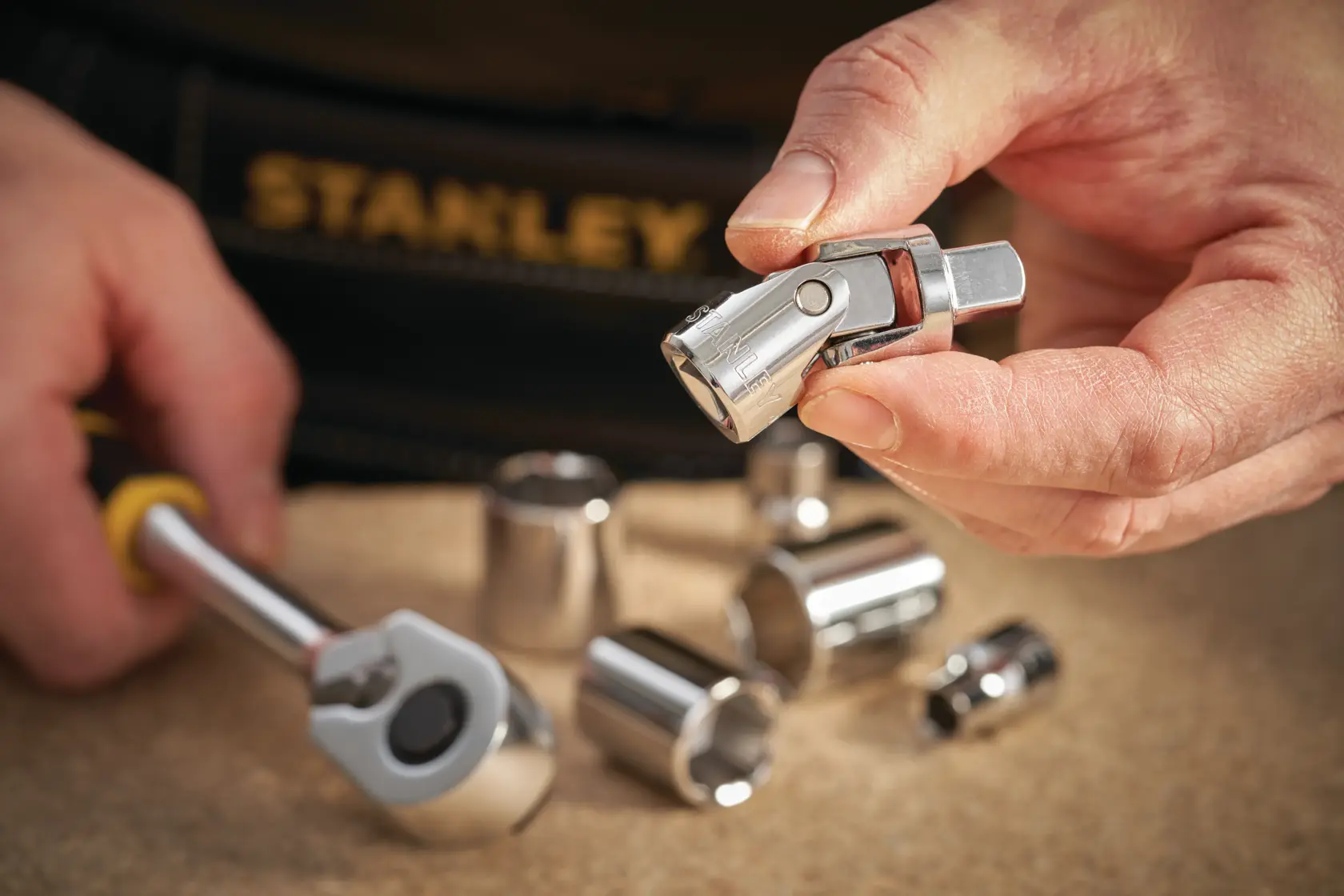 Photo of STANLEY STMT86211-0 socket set with chrome sockets and ratchet tool in hand, workshop setting.