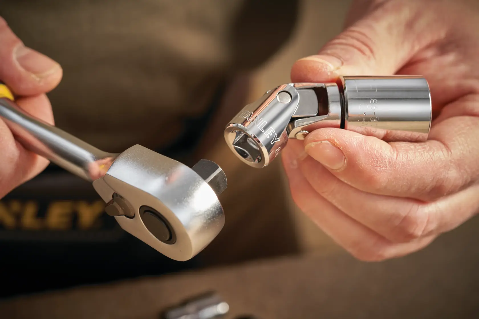 Photo of STANLEY STMT86211-0 socket and ratchet, close-up of hands connecting chrome tool parts.