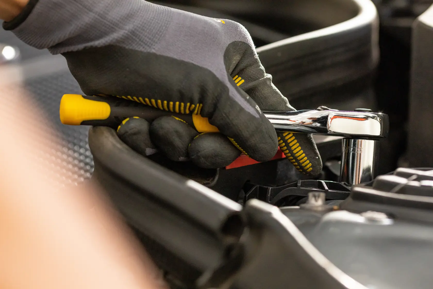 STANLEY STMT86315-0 ratchet wrench in use, close-up of gloved hand working on engine.