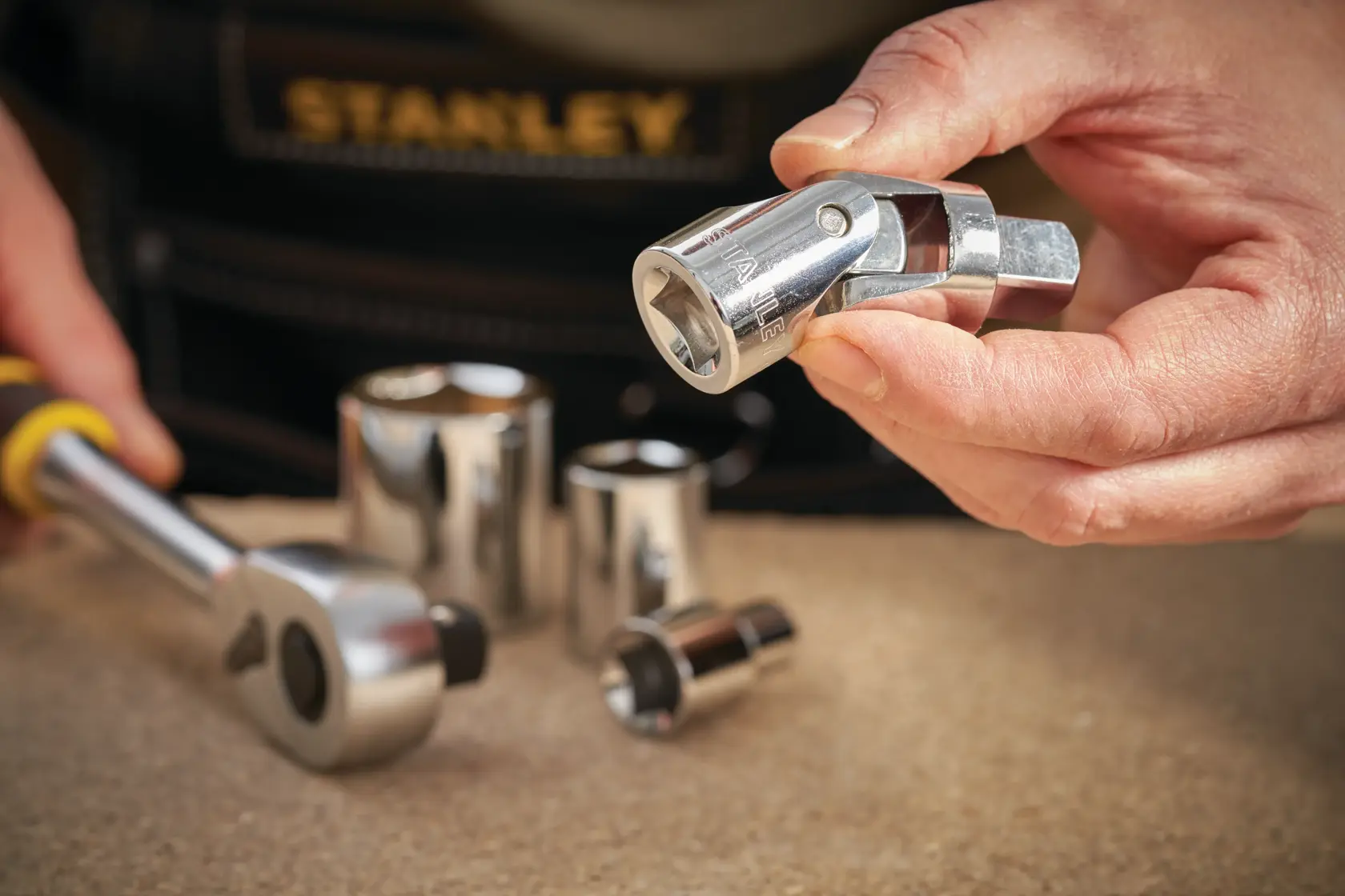 STANLEY STMT86411-0 socket universal joint and ratchet with chrome finish on workbench, photography close-up.