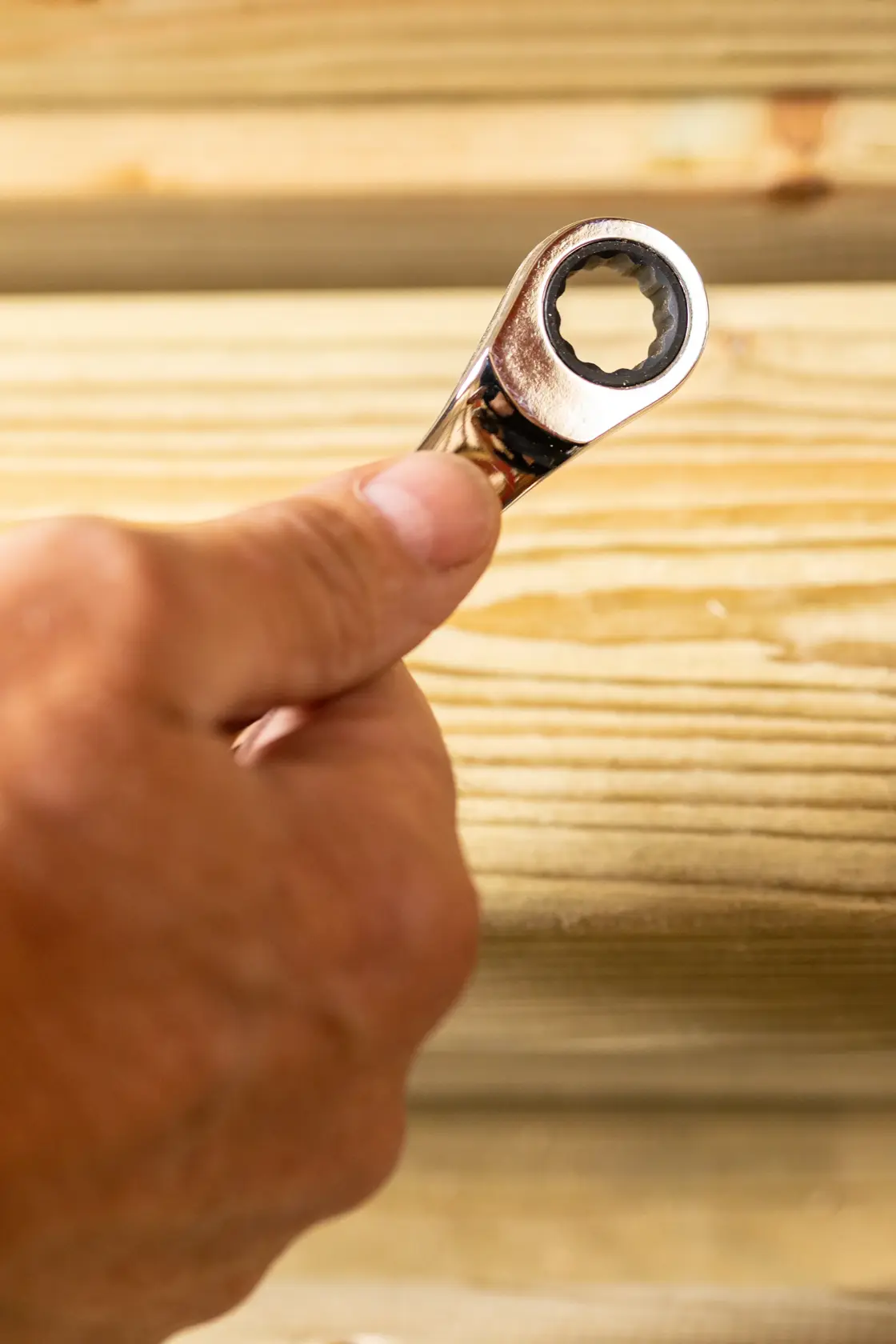 STANLEY STMT89908-0 ratcheting wrench held by hand against light wood background, close-up photography.