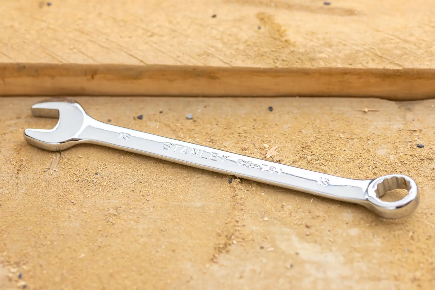 STANLEY STMT95791-0 chrome combination wrench on a wooden surface, product photography.