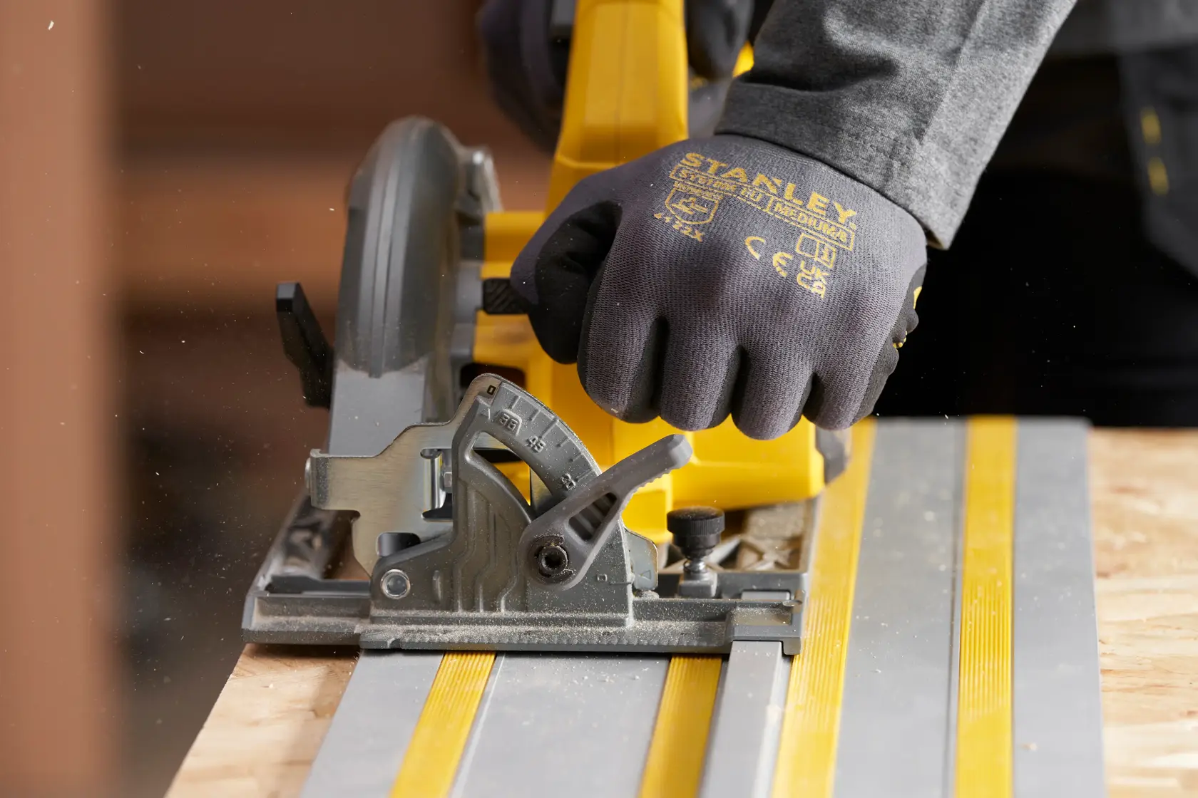 STANLEY STST140-XJ work glove on hand using circular saw on guide rail, close-up photography.