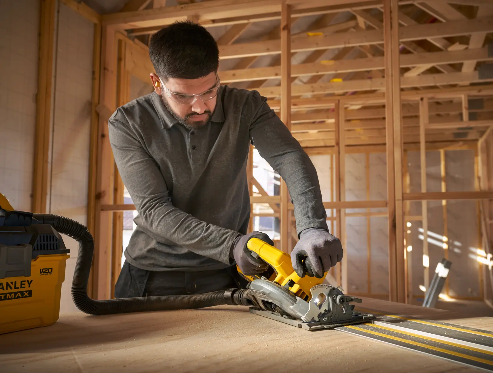 STANLEY STST140-XJ vacuum system in workshop, connected to circular saw during wood cutting, photo from front angle.