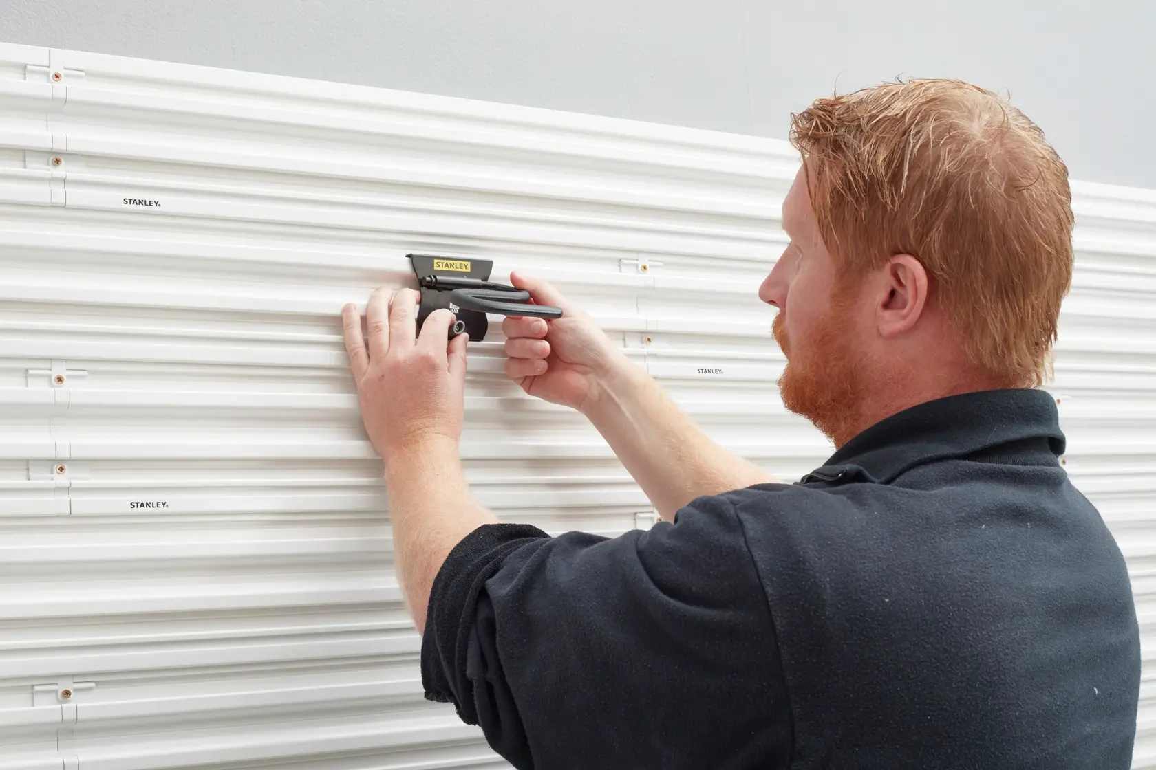 Stanley STST82605-1 photography of wall panel hook installation, white grooves, person adjusting hook.