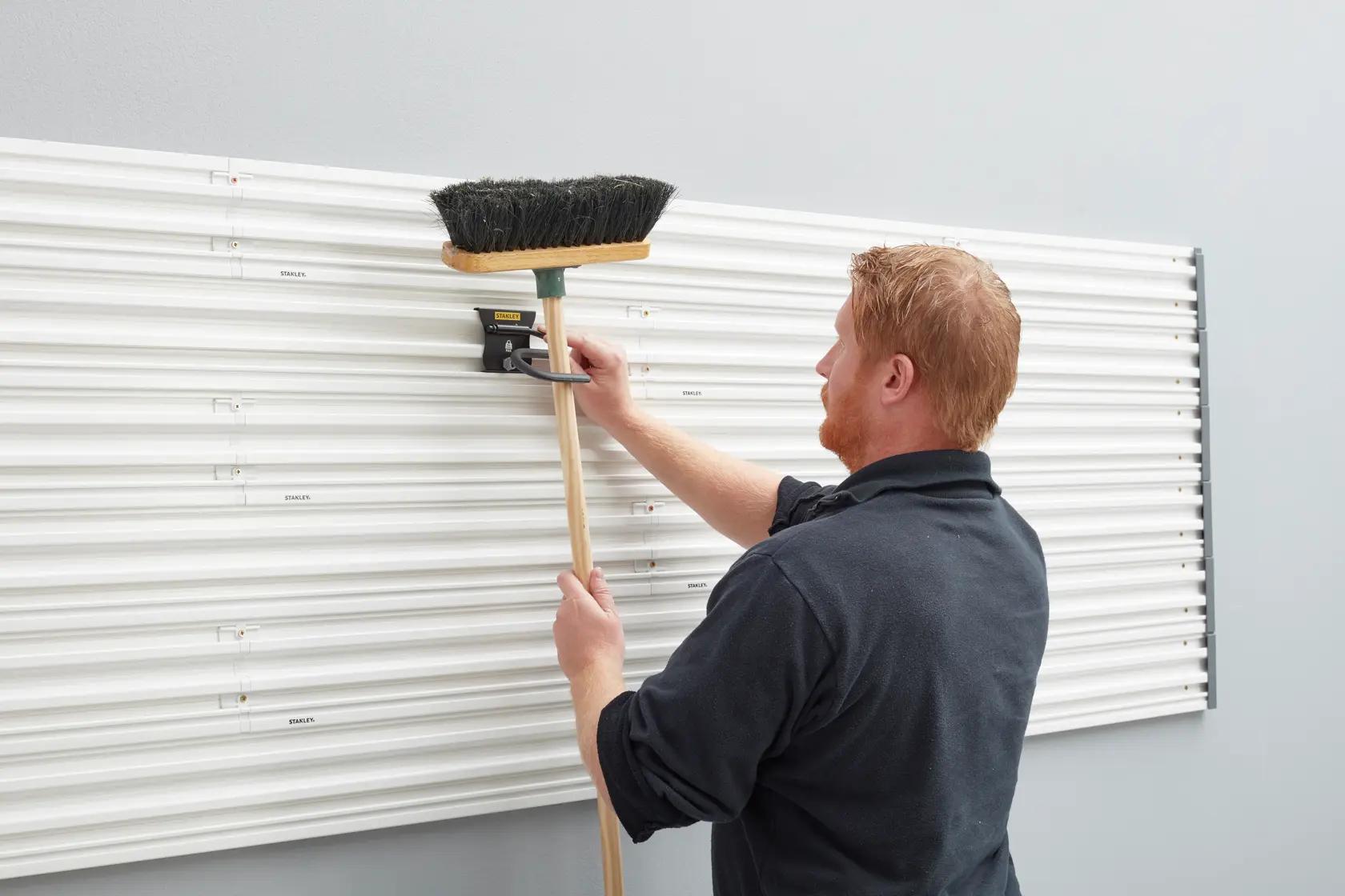 STANLEY STST82605-1 wall organizer with broom positioned on holder, side angle photo.