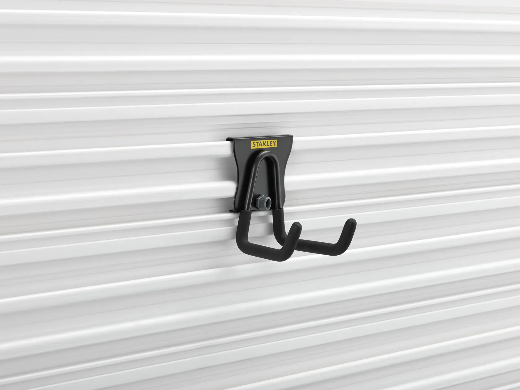 Photo of STANLEY STST82607-1 black wall-mounted utility hook on white panel, side angle.