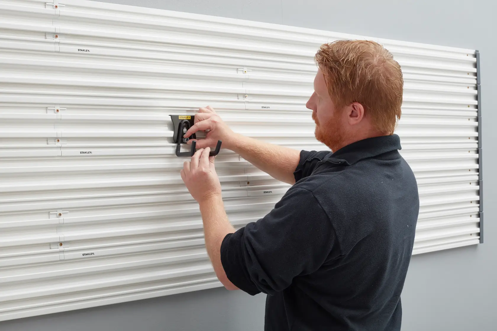 Photo of STANLEY STST82607-1 wall panel system being installed by a person in black shirt.