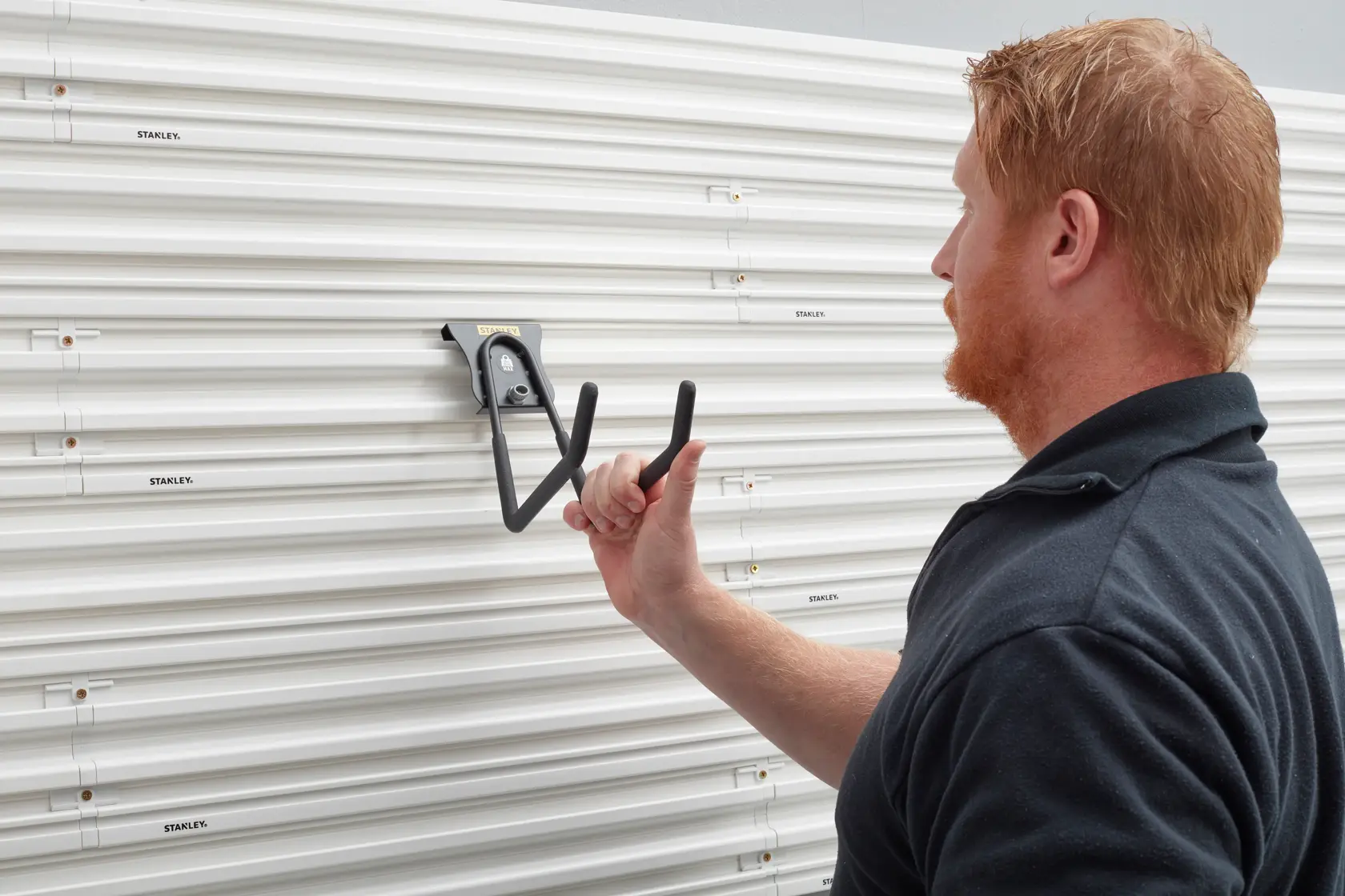 STANLEY STST82608-1 heavy duty wall hook being installed on white slat wall panel, side angle.