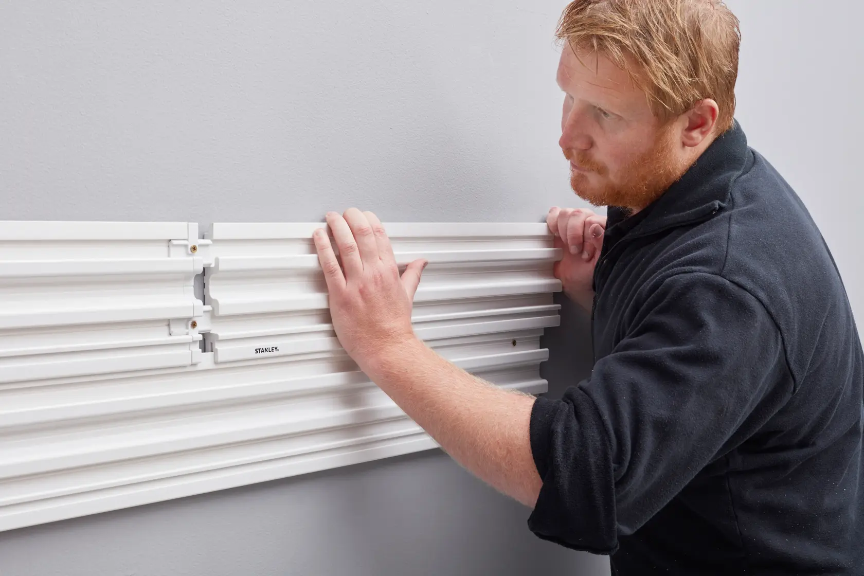 STANLEY STST82610-1 wall panel installation, close-up of hands attaching white mounting panels.