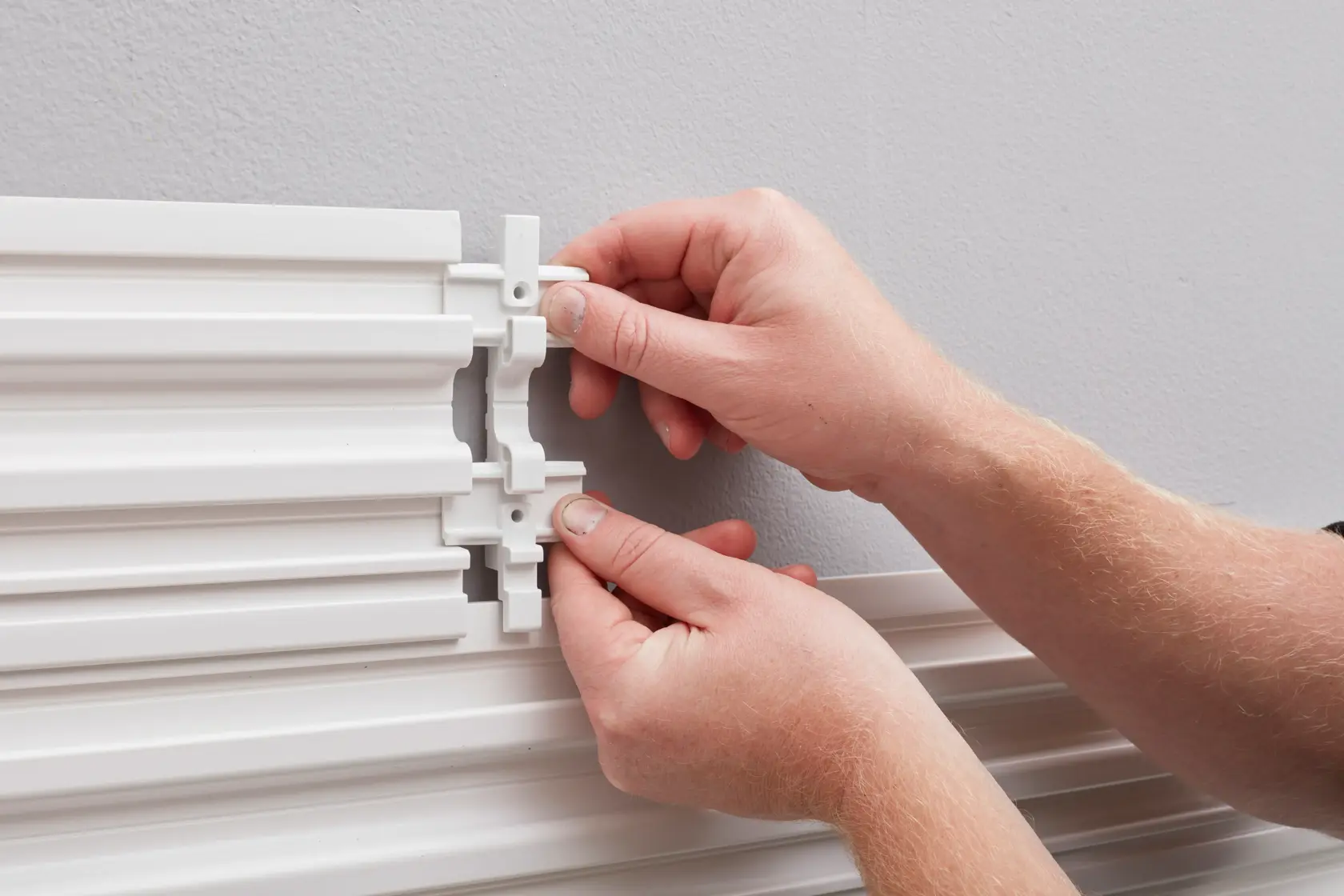 STANLEY STST82610-1 wall panel connector installation, close-up of hands assembling white panels.