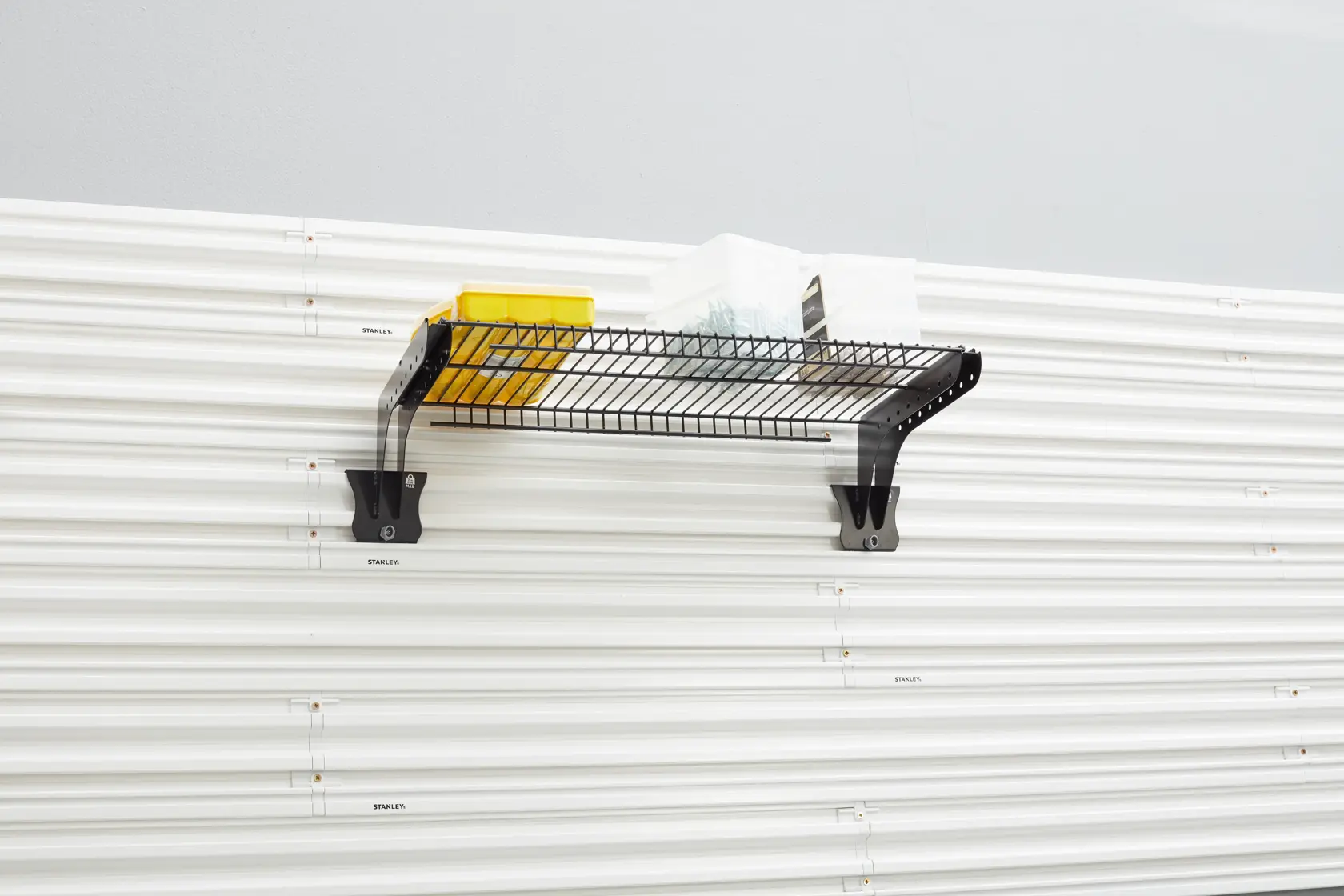 STANLEY STST82613-1 black wire wall shelf with brackets, front angle, holding storage boxes, photography category.