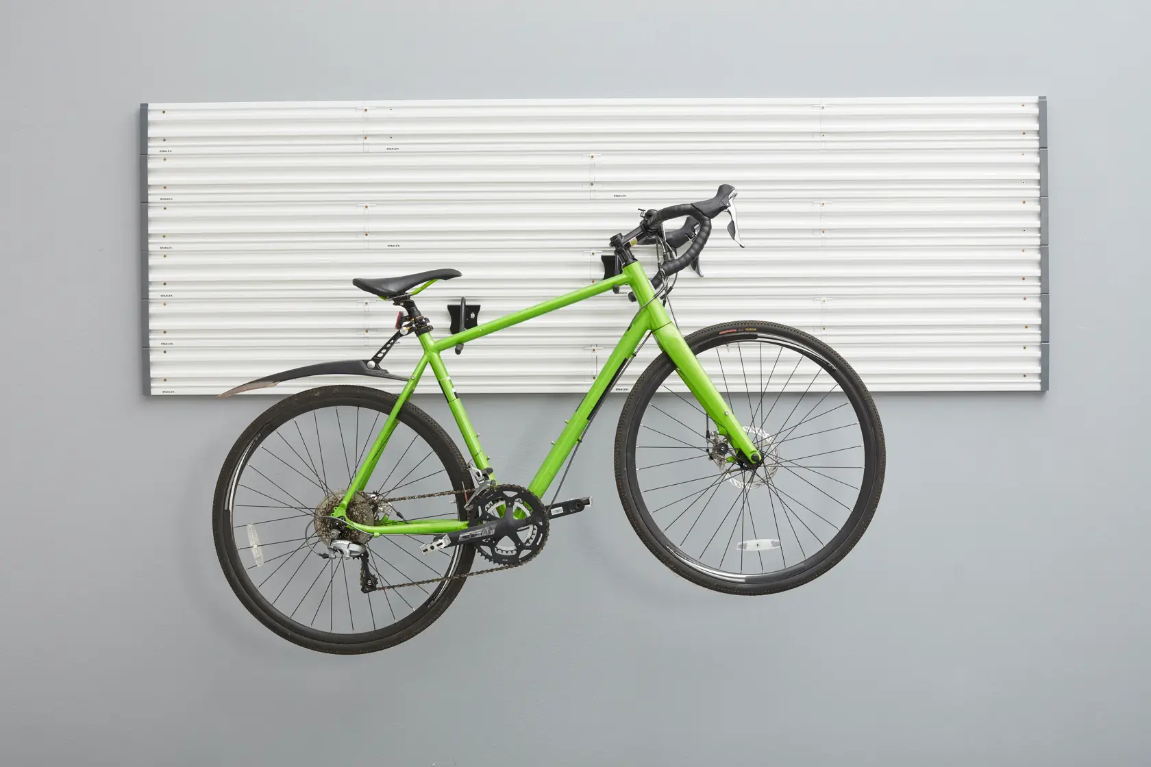 STANLEY STST82615-1 wall storage panel with green road bike mounted on hooks, front view.