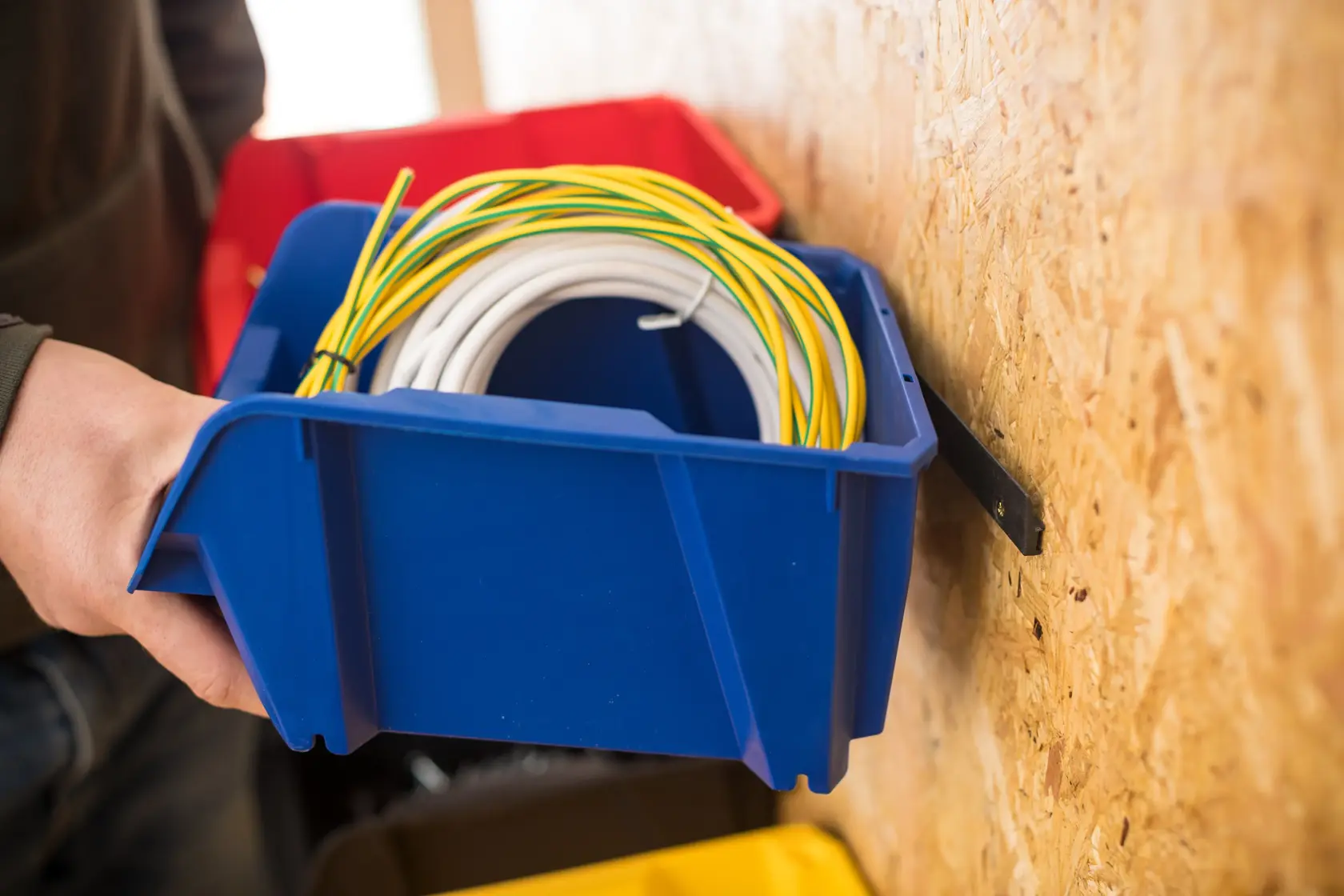 STANLEY STST82740-1 blue storage bin holding coiled wires, photo taken from the side on a wall mount.
