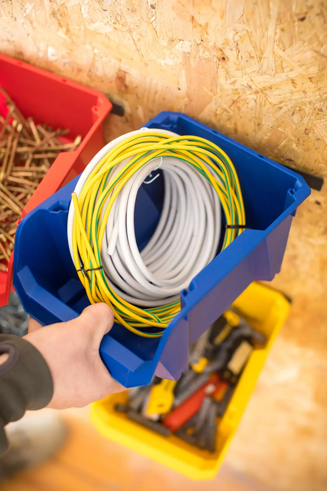 STANLEY STST82740-1 blue storage bin with coiled cable, viewed from above in workshop setting.